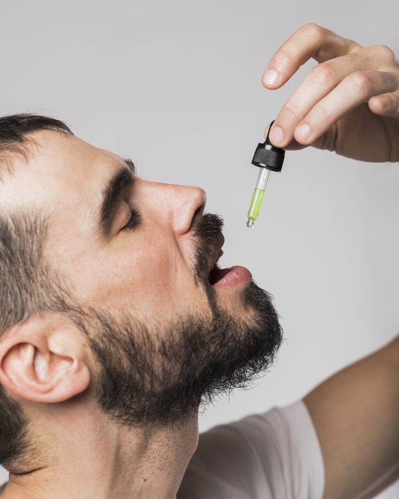 Person taking CBD oil drops under the tongue